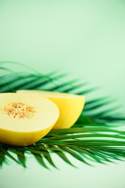 Zoete meloen over tropische groene palmbladen op turkooise achtergrond.