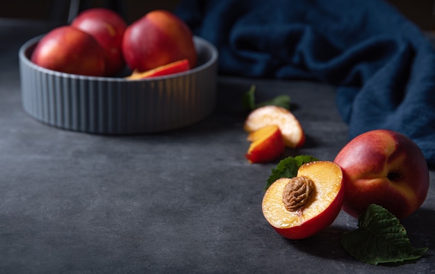 Zoete nectarine in een grijze kom en plakjes op een donkerblauwe achtergrond. Low key concept en kopie ruimte afbeelding