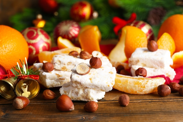 Zoete nougat met sinaasappelen en kerstversiering op tafel close-up