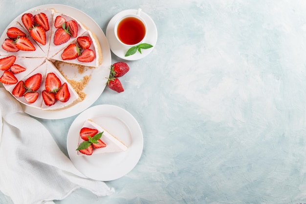 Zoete ontbijtthee en heerlijke kwarktaart met verse aardbeien en munt huisgemaakt recept zonder bakken op een blauwe stenen tafel Kopieer ruimte