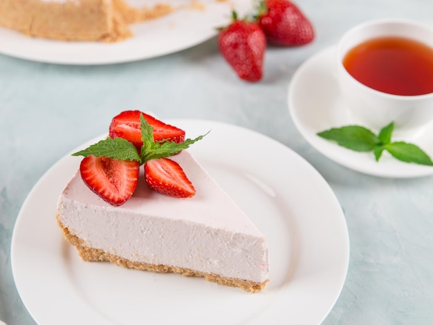 Zoete ontbijtthee en heerlijke kwarktaart met verse aardbeien en munt huisgemaakt recept zonder bakken op een blauwe stenen tafel Kopieer ruimte