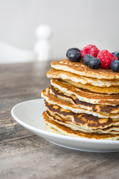 Zoete pannenkoeken met bosbessen en frambozen op rustiek hout