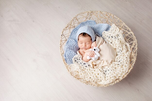 Zoete pasgeboren baby slaapt in een mand. Mooie pasgeboren jongen met berenstuk speelgoed. Kopieer ruimte