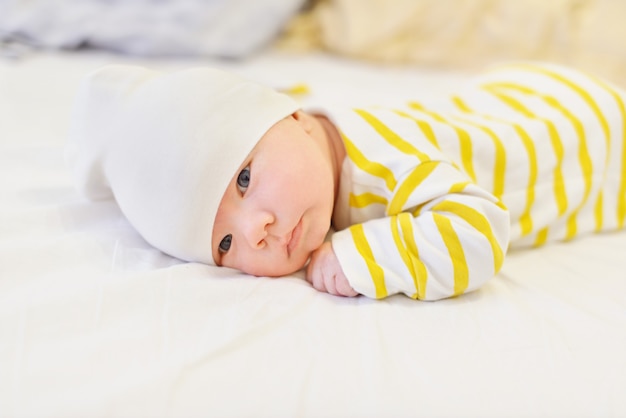 Zoete pasgeboren babyjongen tot op het bed