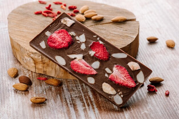 Zoete reep chocolade met fruit en noten op de houten achtergrond