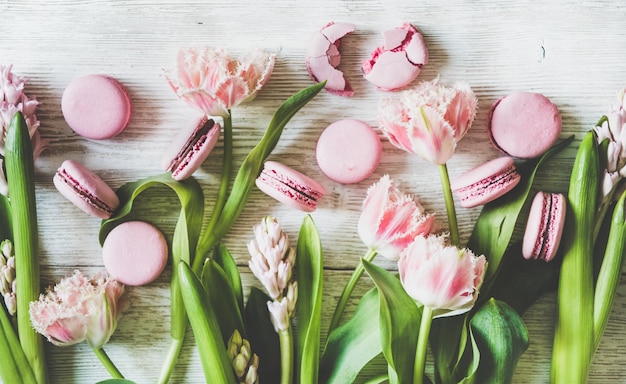 Zoete roze macaronkoekjes en verse lentebloemen bovenaanzicht