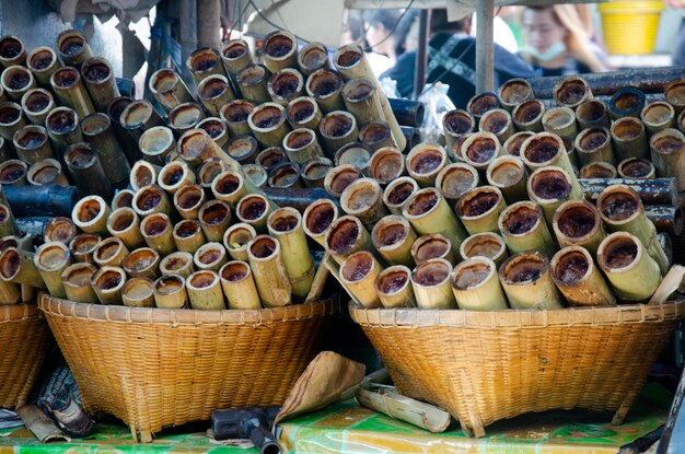 Zoete snack in Thaise stijl Khao Lam of kleefrijst gedrenkt in kokosmelk en geroosterd gebakken in bamboestengel te koop bij de plaatselijke winkel op de Ang Sila-zeevruchtenmarkt in Chonburi, Thailand