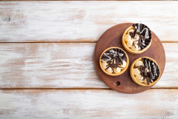 Zoete taartjes met chocolade en kaasroom op een witte houten achtergrond. bovenaanzicht, plat leggen, kopie ruimte.