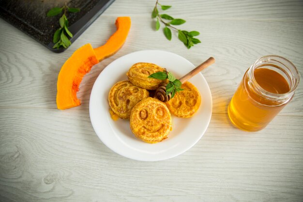 Zoete weelderige pompoenpannenkoekjes met honing in een bord op een houten tafel