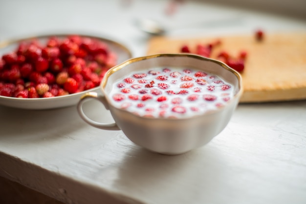 Zoete wilde aardbeien in plaat met melk op houten muur.