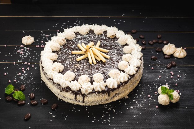 Zoete witte cake met chocolade en meringue op de zwarte houten achtergrond