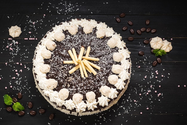 Zoete witte cake met chocolade en meringue op de zwarte houten achtergrond