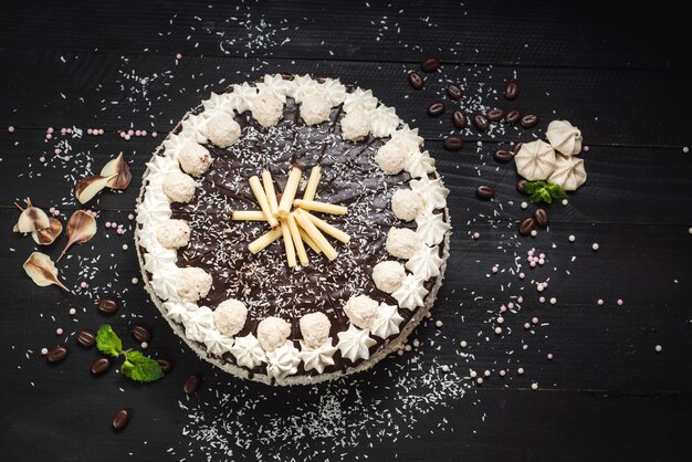 Zoete witte cake met chocolade en meringue op de zwarte houten achtergrond