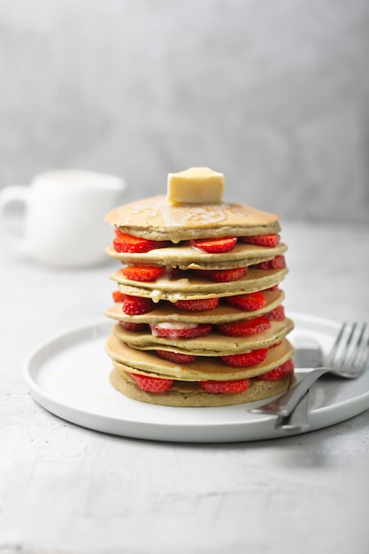 Zoete zelfgemaakte pannenkoeken met aardbeien en boter. Klaar voor het ontbijt.