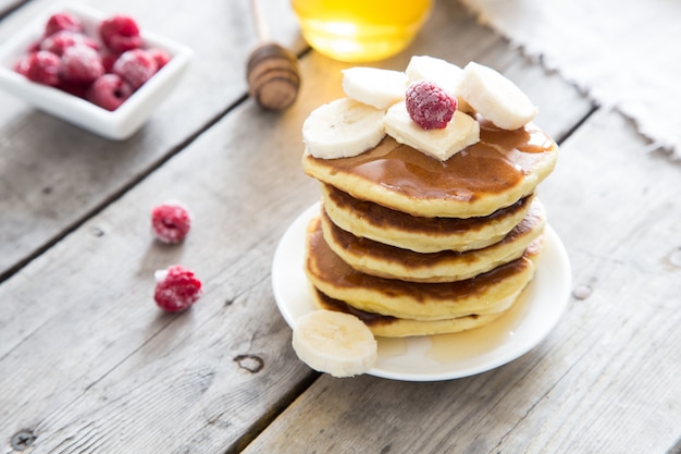 Zoete zelfgemaakte stapel pannenkoeken met boter en honing voor het ontbijt