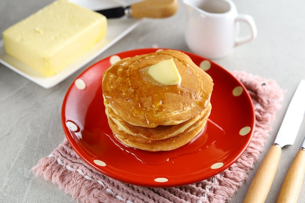 Zoete zelfgemaakte stapel pannenkoeken met boter en honingsiroop als ontbijt