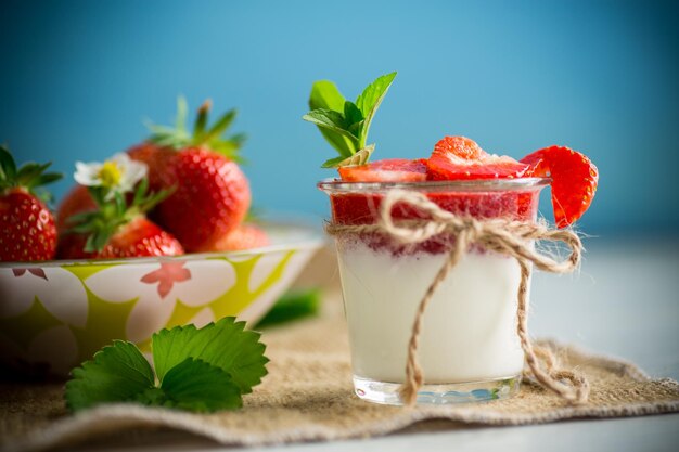 Zoete zelfgemaakte yoghurt met aardbeienjam en verse aardbeien in een glazen beker