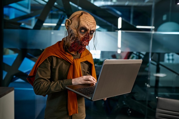 Zombie employee working online on laptop computer in office boardroom at night