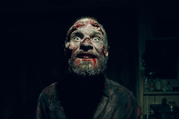 Ritratto di uomo zombie nell'oscurità con il trucco per la festa di halloween