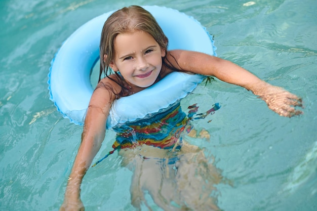 Zomer activiteit. Lief klein meisje dat op een buis zwemt en lacht