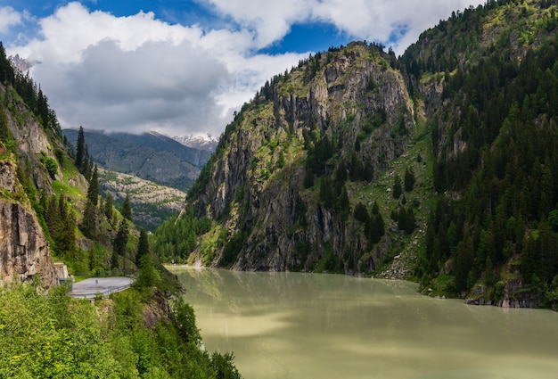 Zomer Alpen berglandschap met troebel water reservoir meer en steile rotsachtige hellingen, Zwitserland