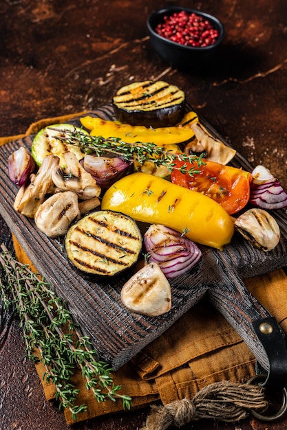 Zomer BBQ met gegrilde groenten paprika courgette aubergine ui en tomaat op een houten plank Donkere achtergrond Bovenaanzicht