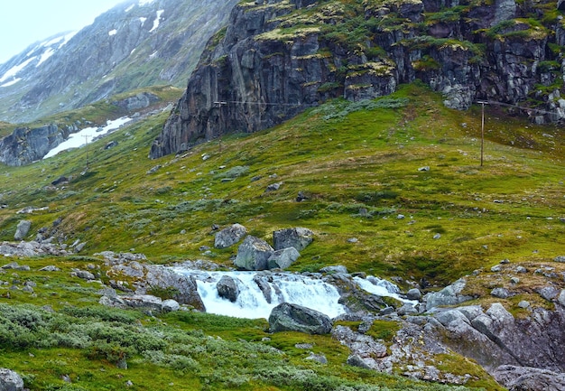 Zomer bewolkt berglandschap met waterval.