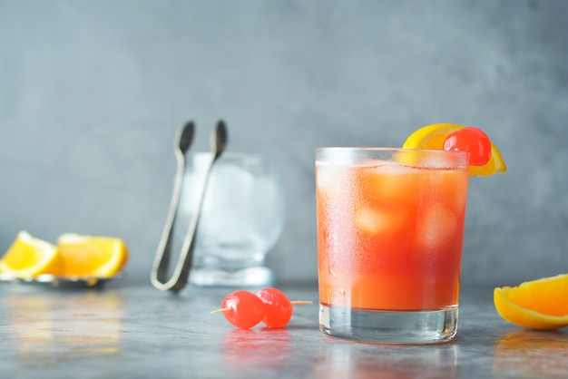 Zomer cocktail. Sinaasappelsap met munt, siroop, fruitschijfjes en kersen met ijs.