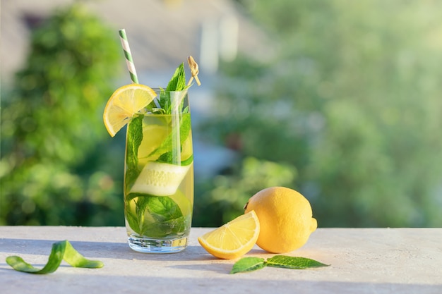 Zomer concept. Limonade of mojito cocktail met citroen, komkommer en munt, koel verfrissend drankje of drankje, buiten. Koud detoxwater met ijs en papierstro, exemplaarruimte.