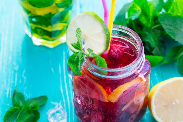 Zomer drankje met frambozen, limoen en ijs op een oude houten tafel