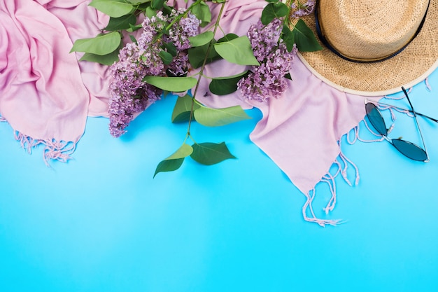 Zomer flatlay met roze sjaal, strohoed en zonnebril op blauw