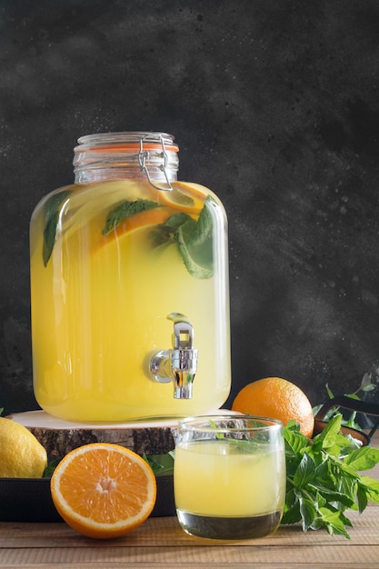 Zomer gezond detox drankje Limonade met sinaasappel, citroen en munt in glazen pot op houten bord