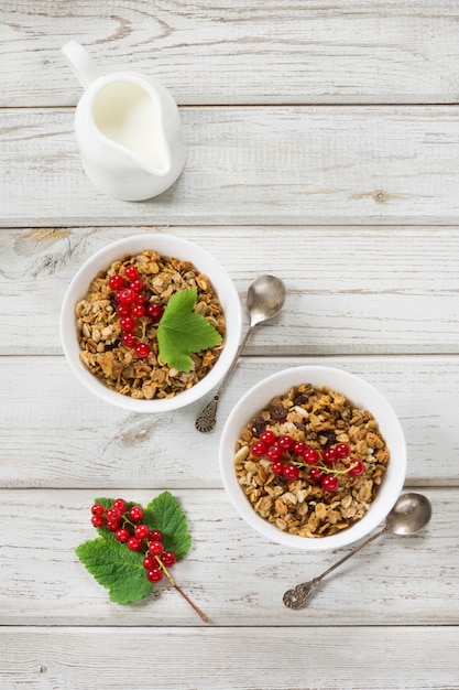 Zomer gezond ontbijt voor twee personen van granola, muesli met melkkannetje met decor van rode aalbes