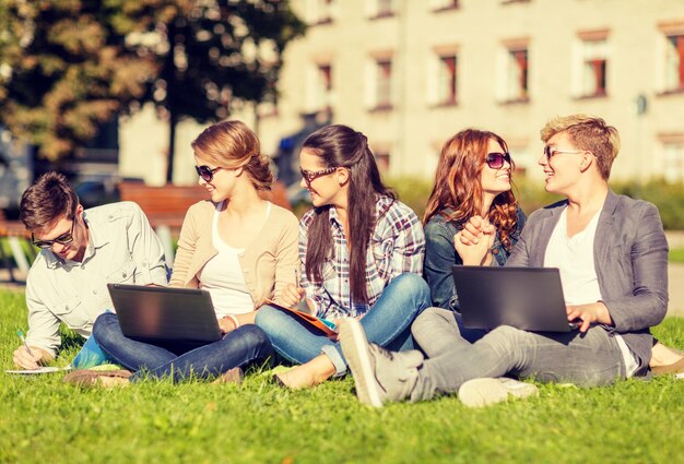 zomer, internet, onderwijs, technologie en campusconcept - groep studenten of tieners met laptop, notebooks en mappen