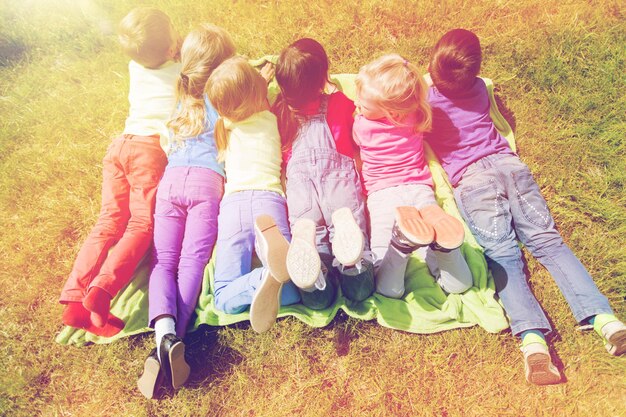 Foto zomer, jeugd, vrije tijd en mensen concept - groep gelukkige kinderen liggend op deken of dekking buitenshuis