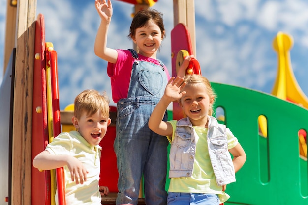 zomer, jeugd, vrije tijd, vriendschap en mensen concept - groep gelukkige kinderen zwaaiende handen op kinderspeelplaats