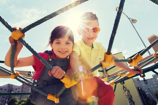 zomer, jeugd, vrije tijd, vriendschap en mensenconcept - groep gelukkige jonge geitjes op kinderspeelplaats klimrek