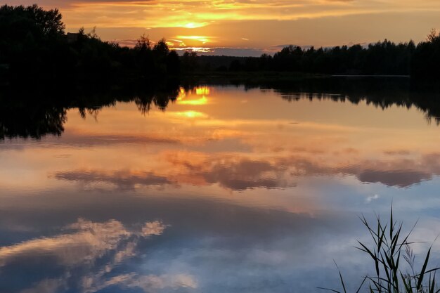 Zomer kleurrijke zonsondergang aan het meer met wolken weerspiegeld in water