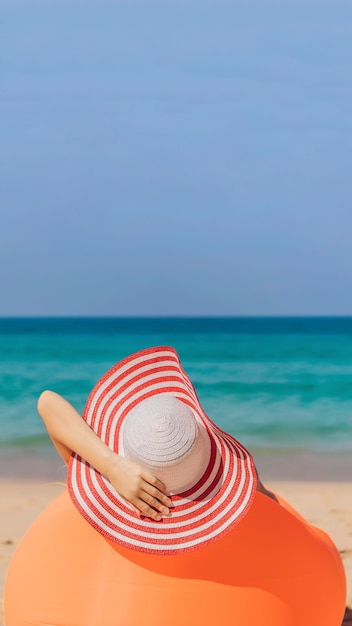 Zomer levensstijl portret van mooi meisje zittend op de oranje opblaasbare bank op het strand van