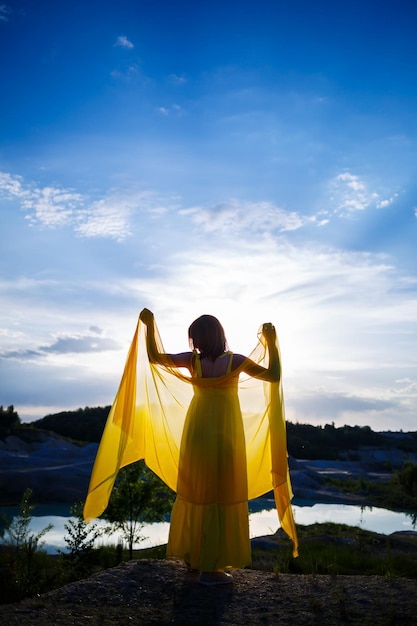 Zomer levensstijl van prachtige gelukkige vrouw die in de natuur loopt. In een lange gele jurk. Romantische stemming. Genieten van de zon. Zonnige dag. Selectieve focus