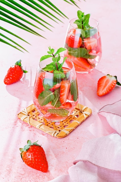 Zomer met munt en aardbei doordrenkt water op roze tafelblad met lange schaduwen bovenaanzicht Zomer fruitige verfrissende cocktail stilleven close-up