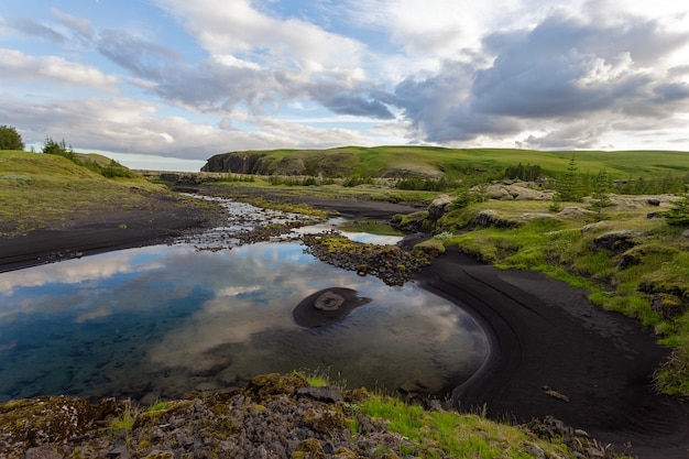 Foto zomer natuur landschap met zwart zand op een rivieroever en wolken in de lucht, ijsland, europa