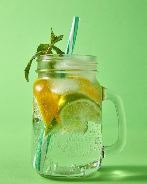 Zomer natuurlijke sprankelende verse limonade in glazen pot met grote luchtbellen op een groene muur. Concept koude alcoholische of niet-alcoholische zomerdranken.