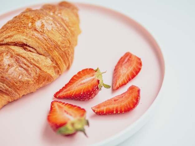 Zomer ontbijt. Roze plaat met croissants en aardbei. Detailopname