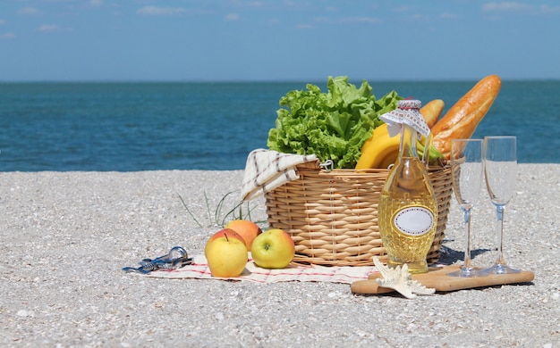 Zomer picknick achtergrond met mand, wijn op het strand door de oceaan