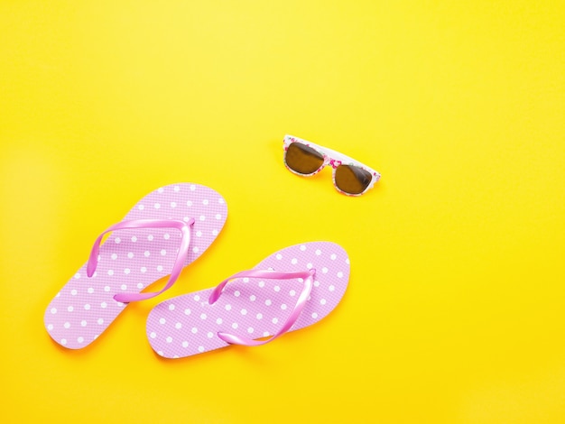 Zomer plat leggen. De toebehoren roze wipschakelaars en zonnebril van strandtoebehoren op gele achtergrond.