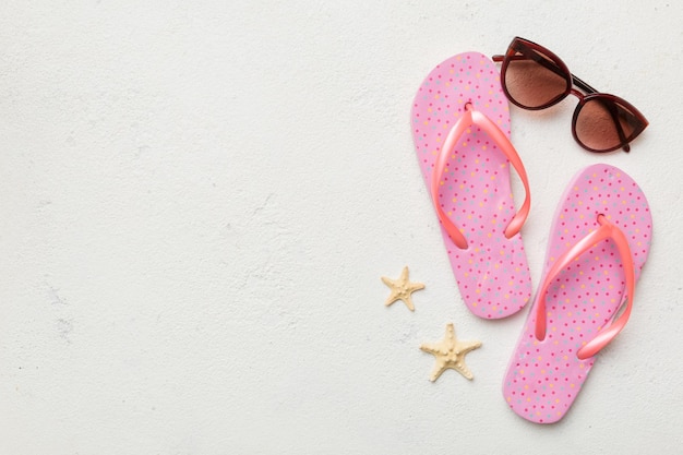 Zomer reizen concept flip flops zonnebril en zeester op wit bovenaanzicht op gekleurde achtergrond