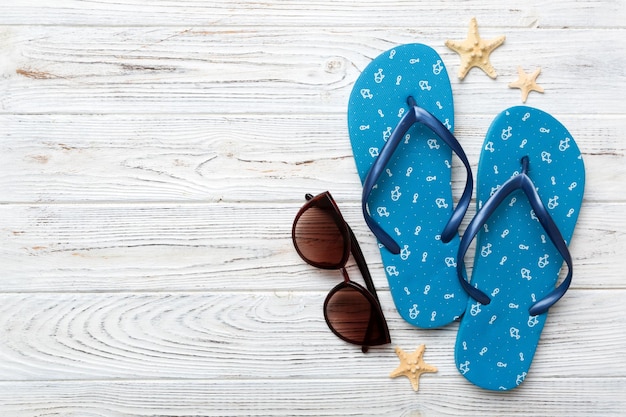 Zomer reizen concept flip flops zonnebril en zeester op wit bovenaanzicht op gekleurde achtergrond