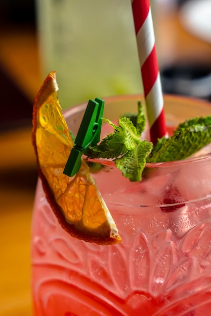 Foto zomer roze cocktail met sinaasappel in een gefacetteerd glas met een rietje