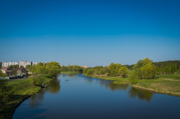 Zomer rurale landschap met rivier en blauwe hemelachtergrond.